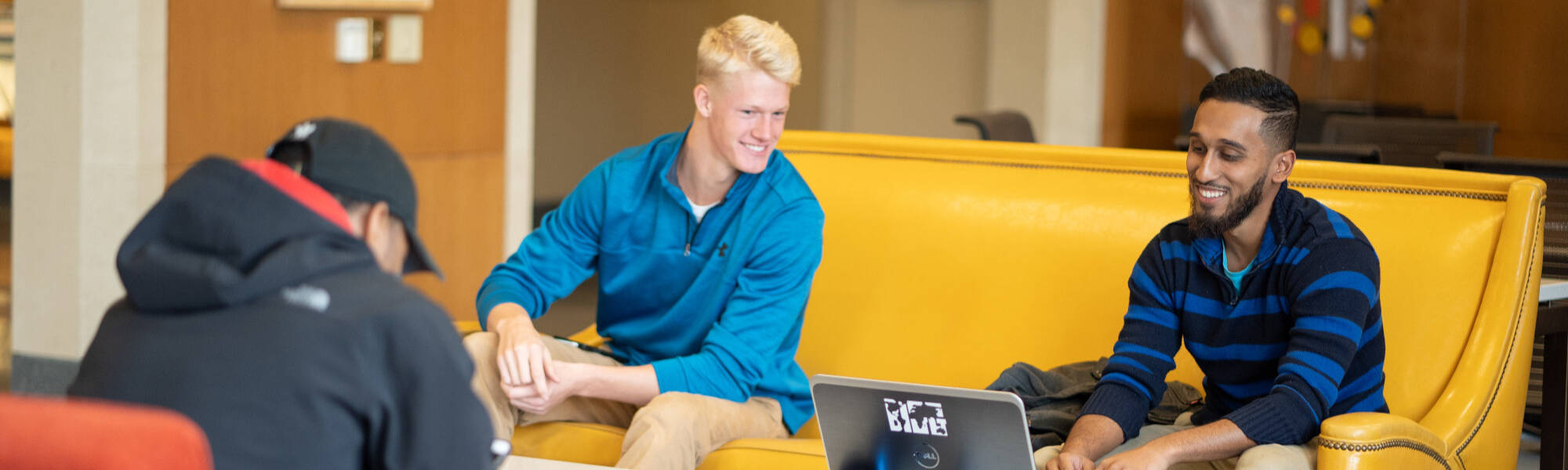 Three students sitting in the Huizenga Exchange, studying on a laptop